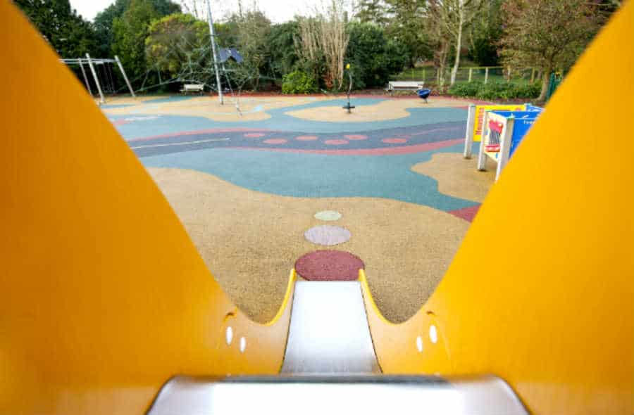 A slide leads to a playfully painted playground surface