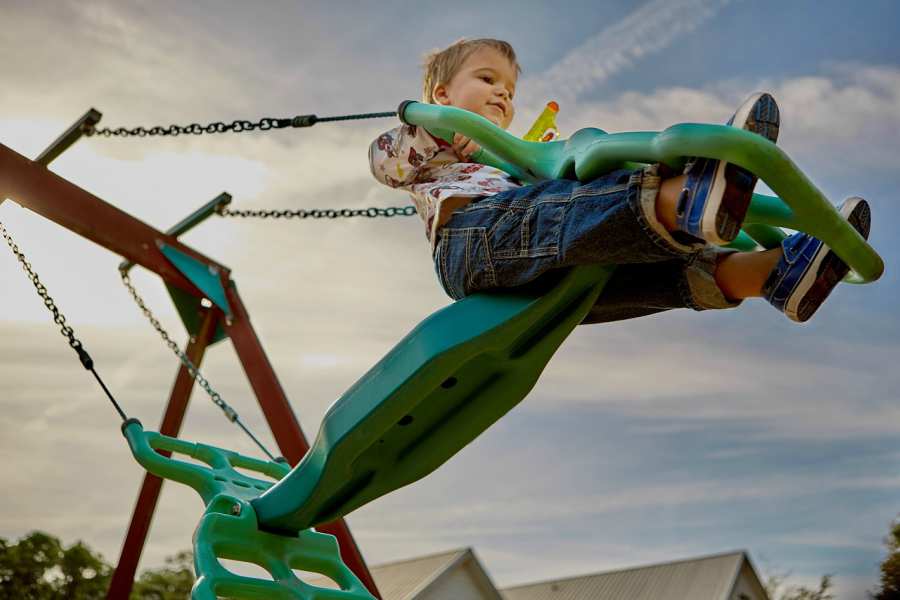 A child riding a swing at a playground in a city neighborhood