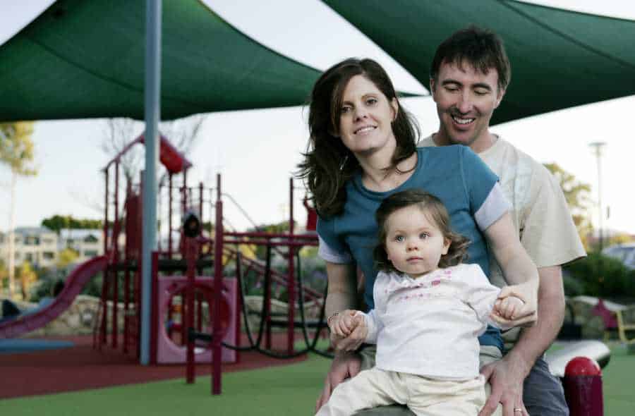 A family at a playground with artificial shade structures