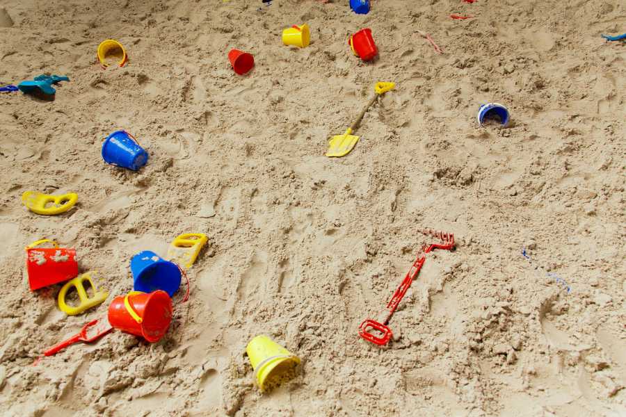 A sandbox filled with toy shovels, buckets, and other tools