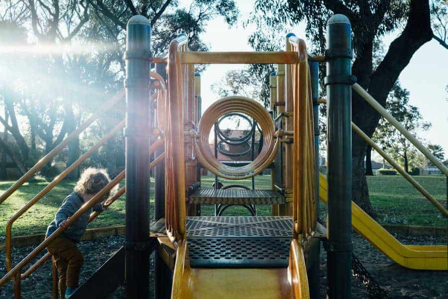 A small child climbing the stairs to reach the top of a slide