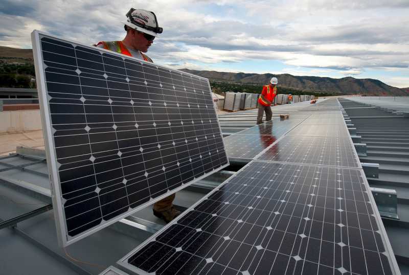 Technicians installing solar panels on a building's roof