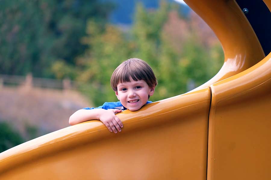 Boy playing on a large spiral slide at a playground equipment installation in Austin, Tx