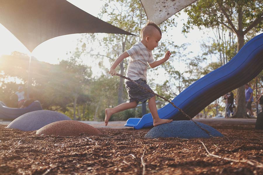 Boy running on a playground with natural elements - Playground Equipment Services in Austin TX