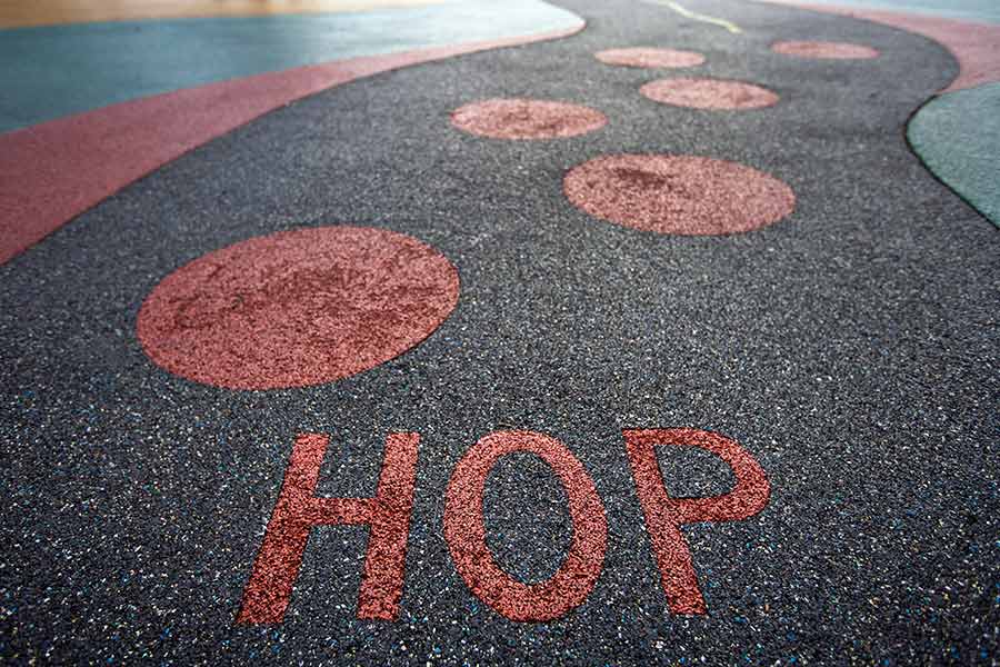 Colorful pour-in-place rubber surface on a playground with the text "HOP"