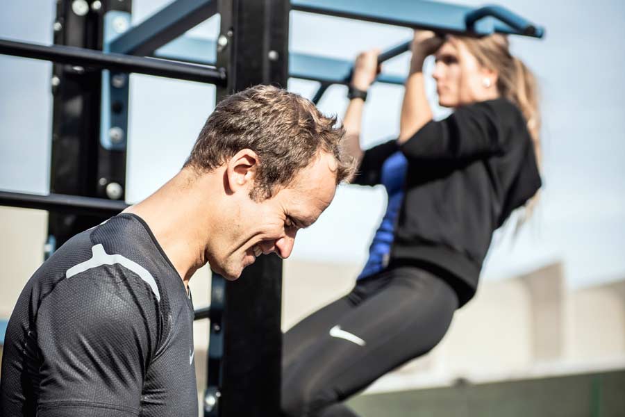 Man and woman using outdoor exercise equipment