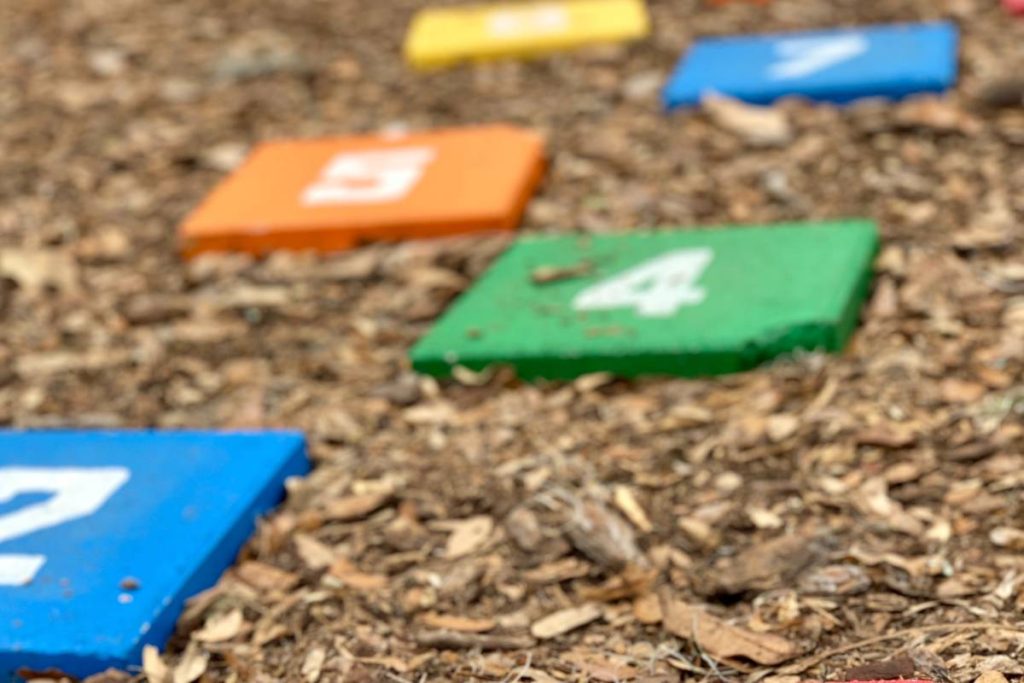 Wooden hopscotch blocks on a mulch playground surface