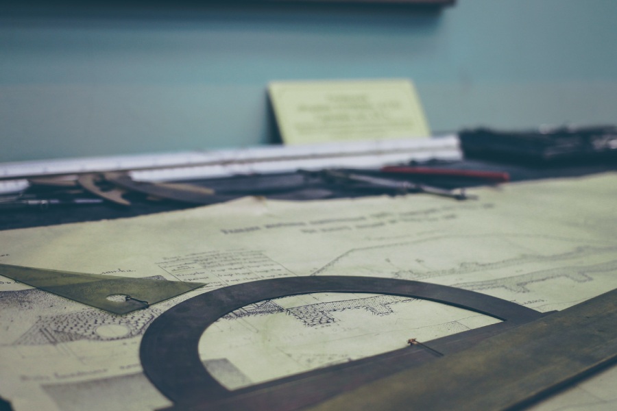 Blueprints spread out on a table with protractor and ruler