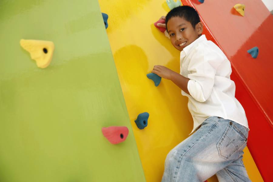 Boy climbing a colorful rock climbing wall at a playground