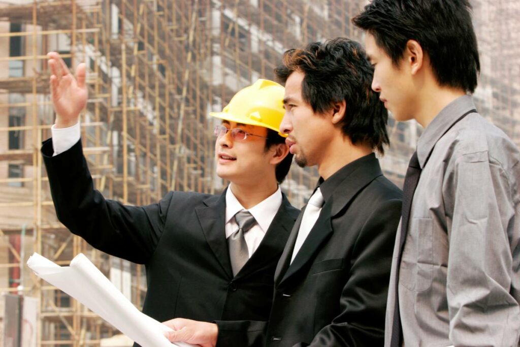 Construction manager discussing commercial building plans with two business men at a work site