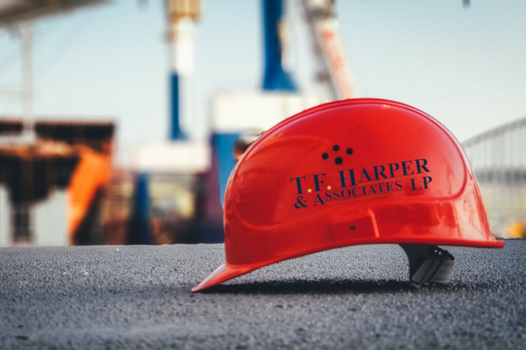 Orange construction hat with a T.F. Harper & Associates LP logo