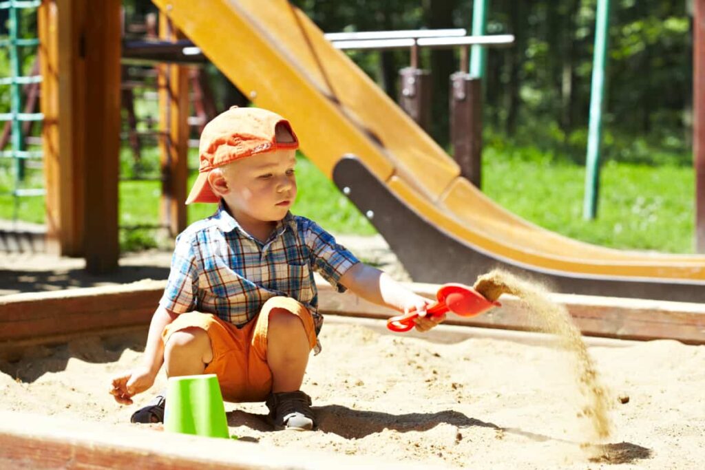 kid playing in a sand box in the play space