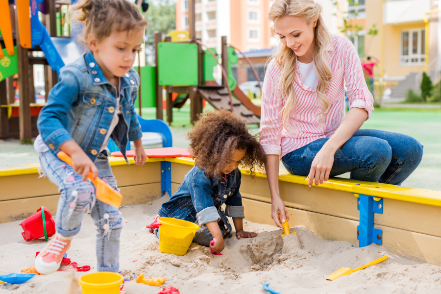 An image of a loving mther playing with her children at the playground during summer time