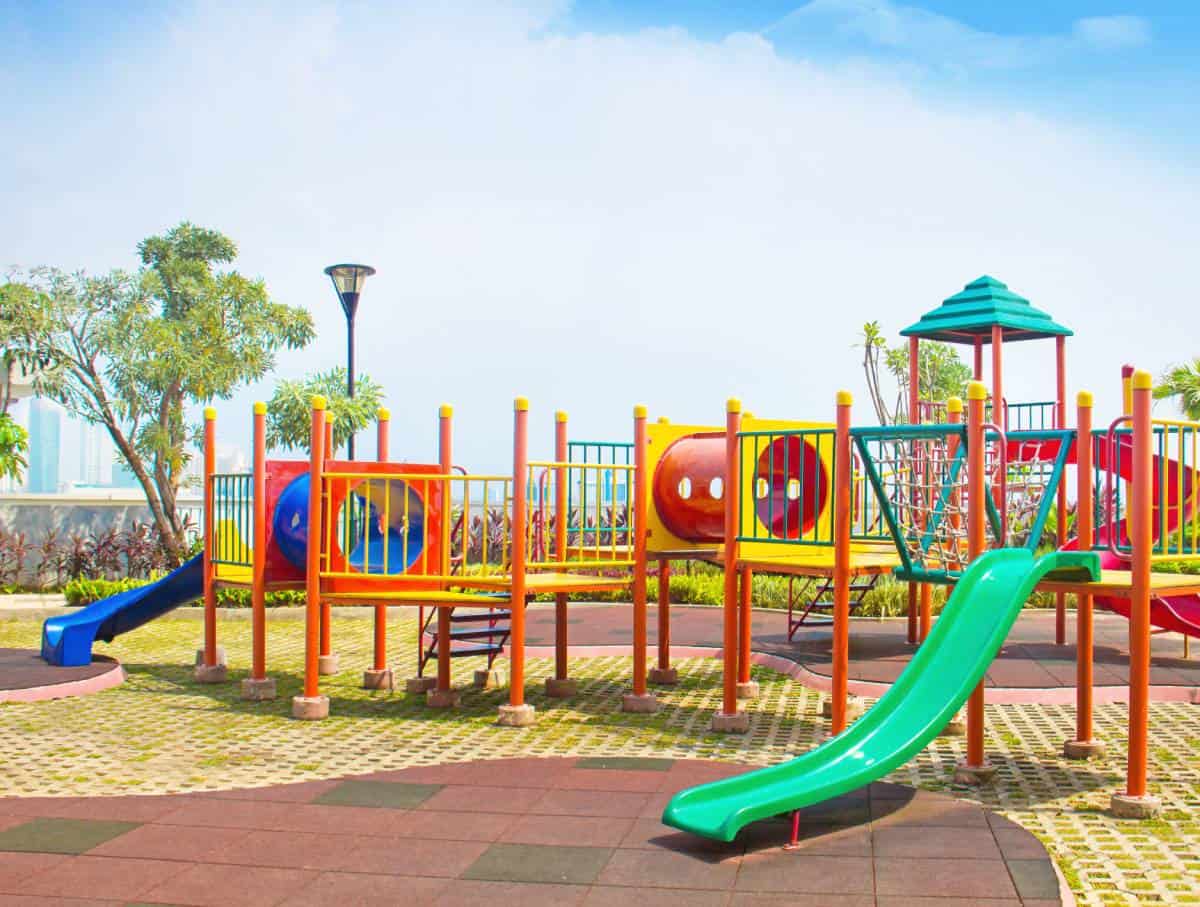 A wooden picnic table, part of playground equipment, on green grass.