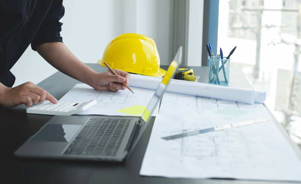 A person planning an Austin construction project with blueprints and laptop.