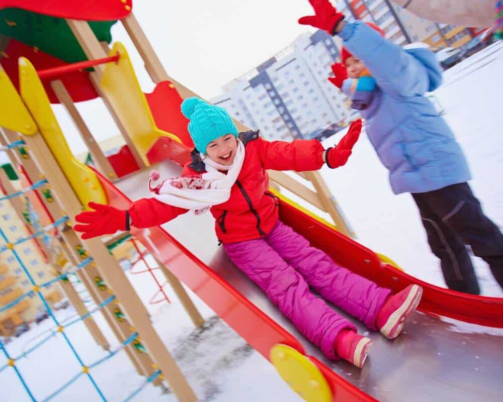 A kid playing on colorful Austin playground equipment in the snow.