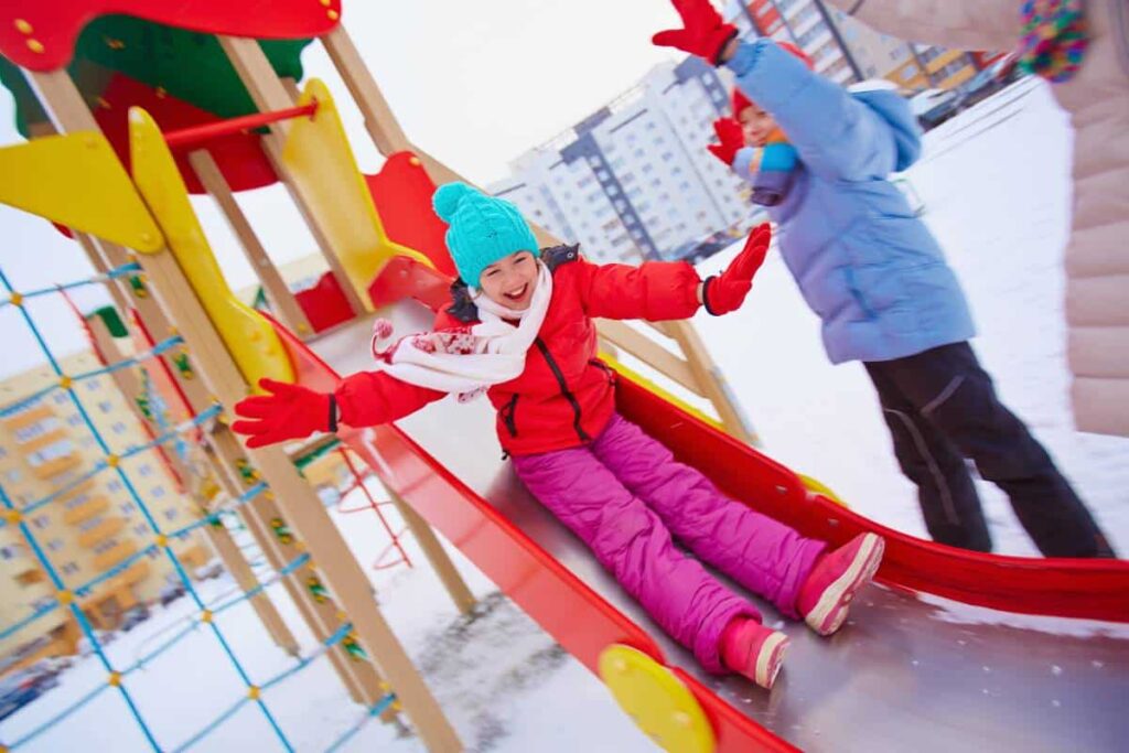 A kid playing on colorful Austin playground equipment in the snow.