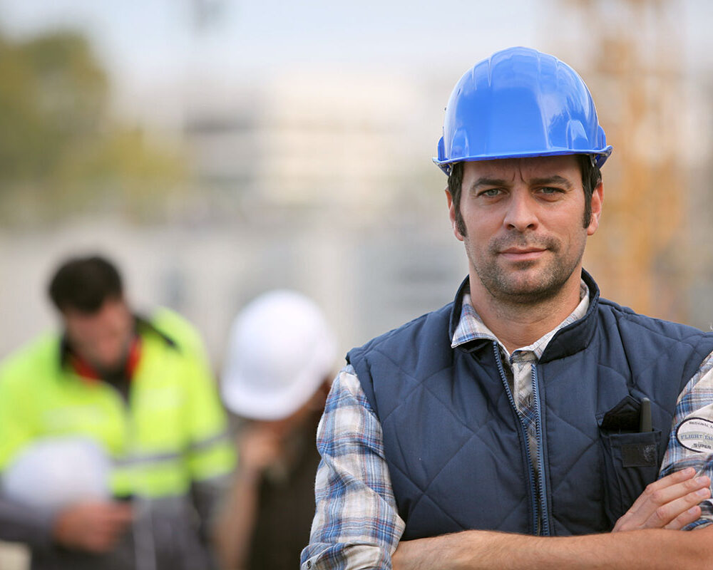 A foreman is standing confidently overseeing a construction job site.