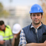 A foreman is standing confidently overseeing a construction job site.