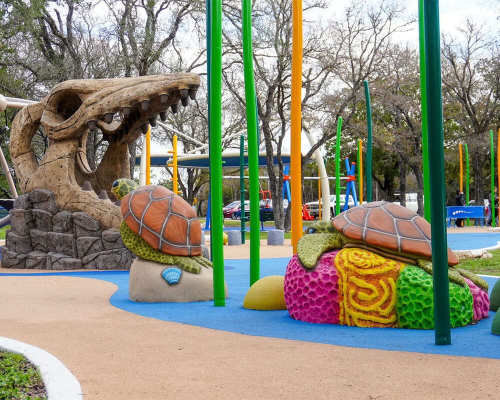 Dinosaur sculpture and colorful play area at an Austin playground.