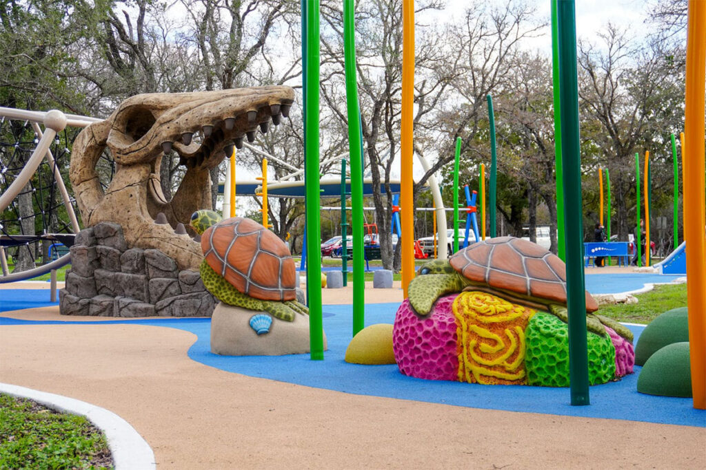 Dinosaur sculpture and colorful play area at an Austin playground.
